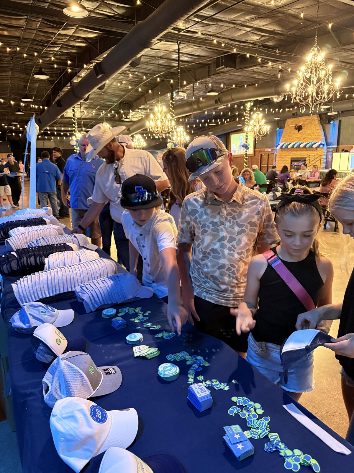 Attendees shopping and browsing a merchandise display with decorative lights at an evening event or festival