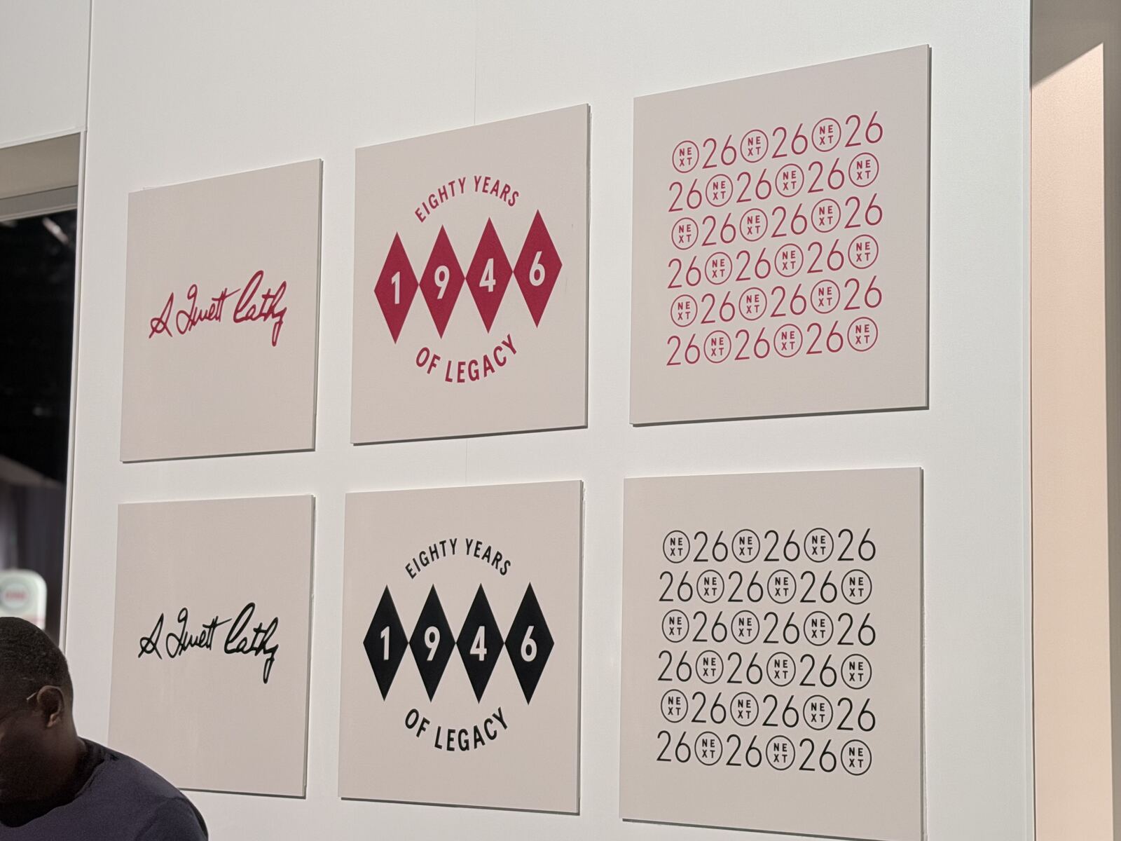 Display wall with framed artwork and anniversary milestone designs at an event booth